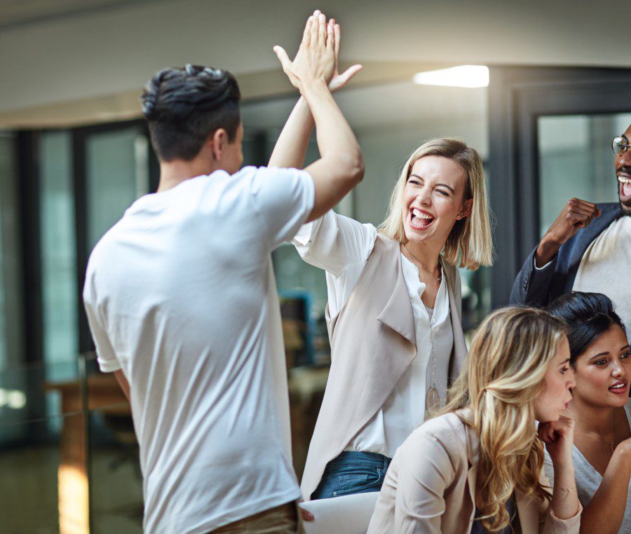 Group celebrating with high-fives in office.